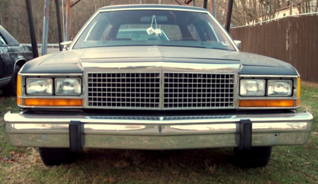 Front view of a boxy tan 1980s full-size Ford with chrome egg-crate grille and quad headlights