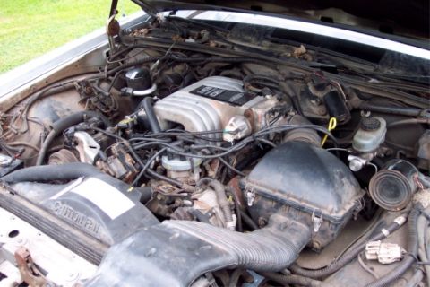 1988 Mercury Grand Marquis - The engine bay of a car, showing the V8 engine, air intake, and various hoses and wires.