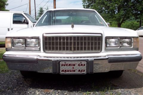 1988 Mercury Grand Marquis - A white 1988 Mercury Grand Marquis is parked outside, showing its front grille and a custom license plate.