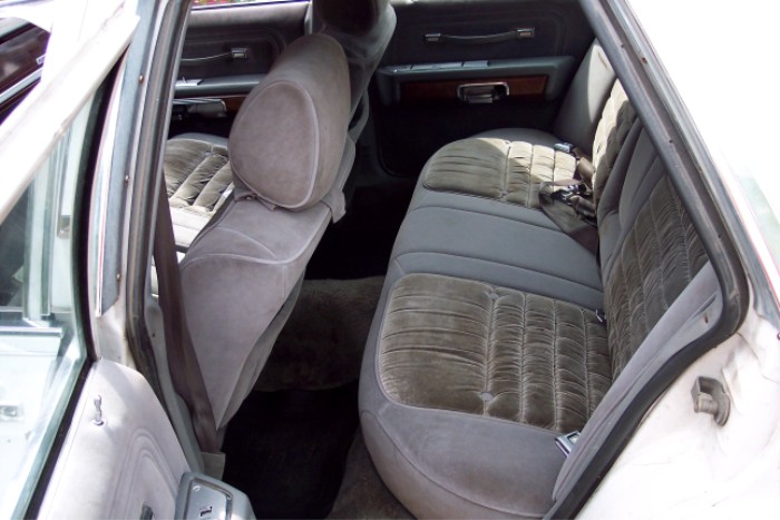 Back seat and door panel of a car. The seats are upholstered in a patterned grey fabric