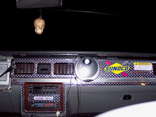 Car dash customized with diamond-plate panels, Sunoco decal and skull air freshener