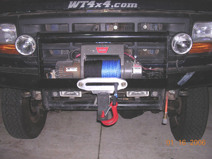 Black Ford front end with Warn winch, blue synthetic rope, red hook, grille guard