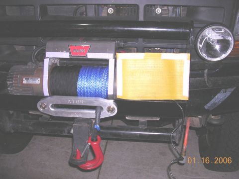 1994 Ford Bronco - Front view of a vehicle's winch system, a Warn winch with blue rope and a red recovery hook.