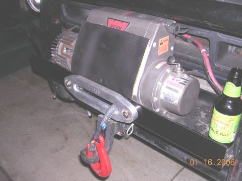 1994 Ford Bronco - A Warn XD9000i winch is mounted on the front bumper, with a red hook and rope attached.