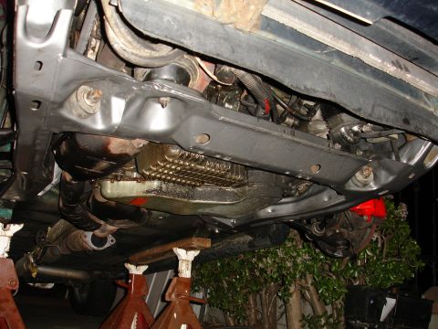 1993 Ford Taurus - Car's subframe and engine oil pan are visible from below, resting on jack stands.
