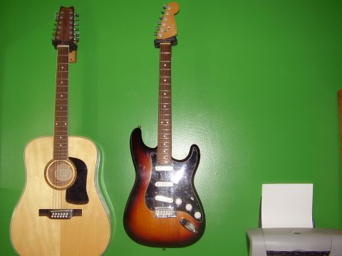 1996 Ford F-150 - Two guitars, a 12-string acoustic and a sunburst electric, are mounted on a bright green wall.