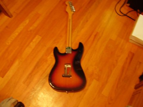 1996 Ford F-150 - An electric guitar with a sunburst finish rests on a polished wooden floor, with a portion of a white box and some cables visible in the ba…