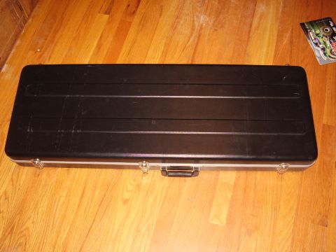 1996 Ford F-150 - A black guitar case rests on a polished wooden floor, with a sticker visible in the upper right corner.