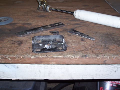 1988 Suzuki Samurai - Metal parts and a shock absorber are laid out on a workbench, suggesting a repair or modification project.