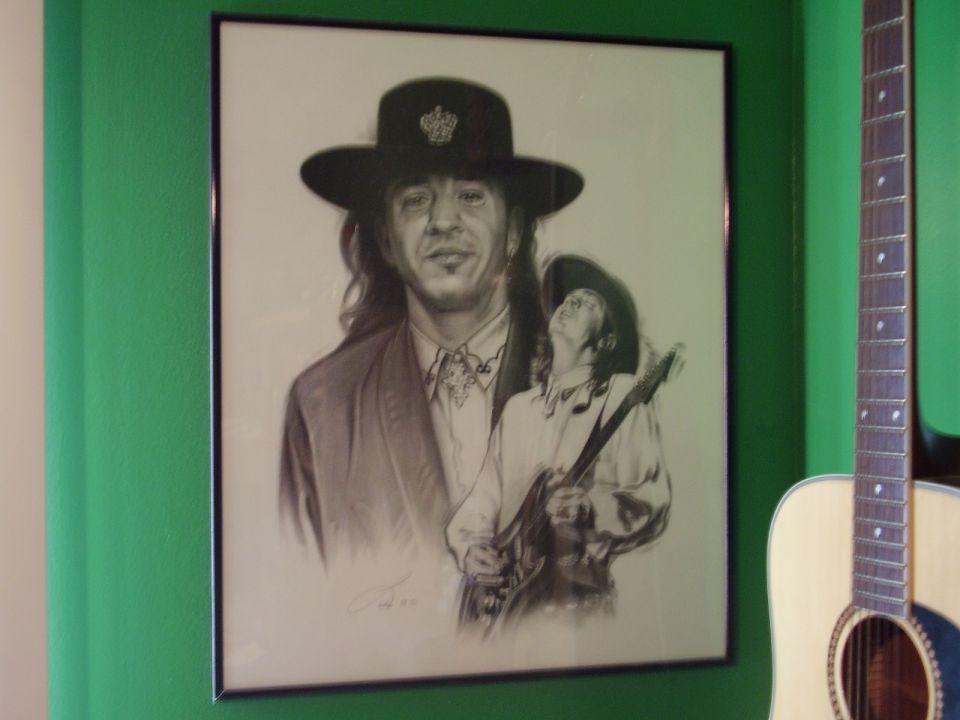 Drawing of Stevie Ray Vaughan playing guitar, with a smaller figure of him also playing guitar in the background. An acoustic guitar is visible to the right