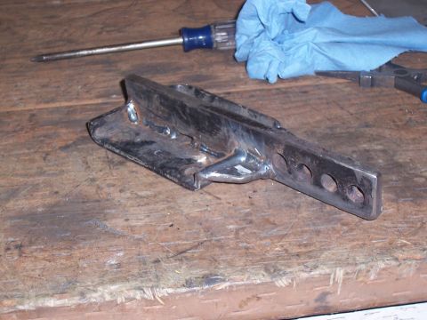 1988 Suzuki Samurai - A custom metal bracket, likely for off-road modification, rests on a wooden surface next to tools.
