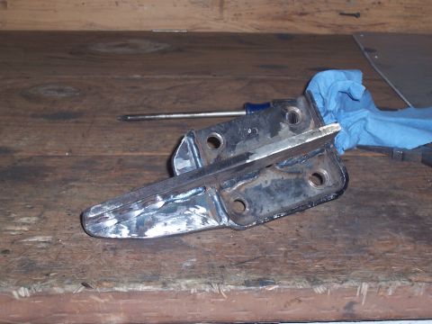 1988 Suzuki Samurai - Close-up of a metal bracket that has been modified, resting on a workbench.