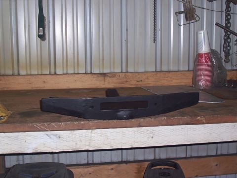 1988 Suzuki Samurai - A black aftermarket bumper sits on a wooden workbench in a garage setting.