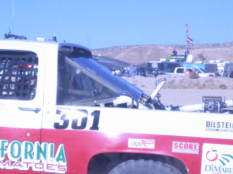 1990 Ford Bronco - Close side view of the white-and-red number 301 race truck cab showing the roll cage, Bilstein and sponsor decals under a clear blue sky.