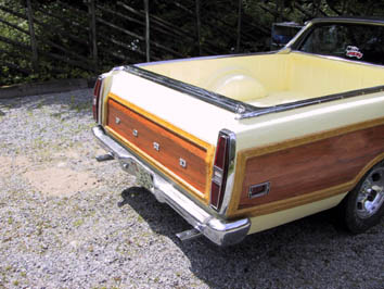 1970 Ford Ranchero - This 1970 Ford Ranchero features a distinctive wood-paneled body and a yellow cargo bed, seen from the rear.