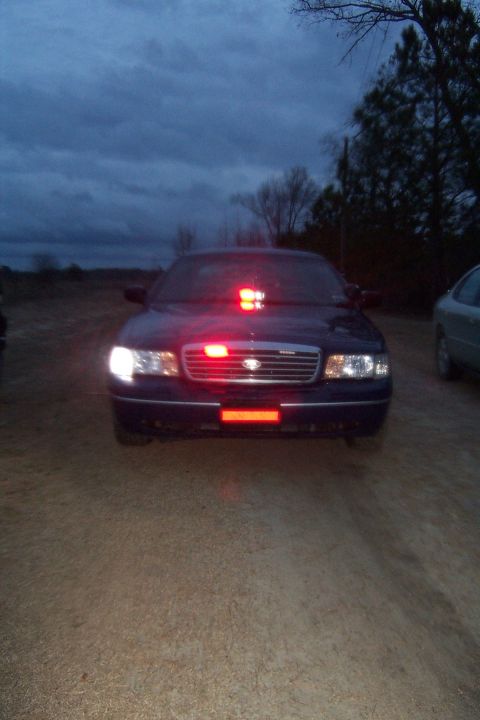 1998 Ford Crown Victoria - Front view of a 1998 Ford Crown Victoria police car with emergency lights activated at dusk.