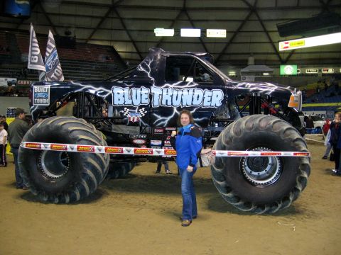 1976 Ford F-150 - A monster truck named 'Blue Thunder' is displayed with a woman posing in front of it.