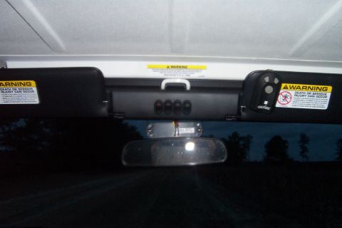 2006 Jeep Wrangler - The overhead console features four buttons and a grab handle, with warning stickers on both sun visors.