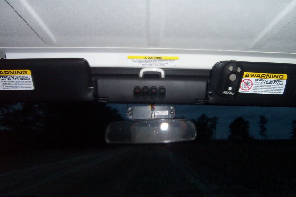 Interior shot of a vehicle's overhead console with warning labels on the visors and a rearview mirror