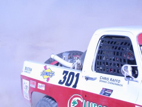 1990 Ford Bronco - Close-up of the rear of race truck 301 showing a mesh window net, spare tire, and Sunoco and Bilstein sponsor decals.
