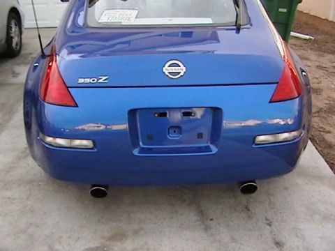 2003 Nissan 350Z - The rear of a blue Nissan 350Z is visible, with its distinctive taillights and dual exhaust pipes.