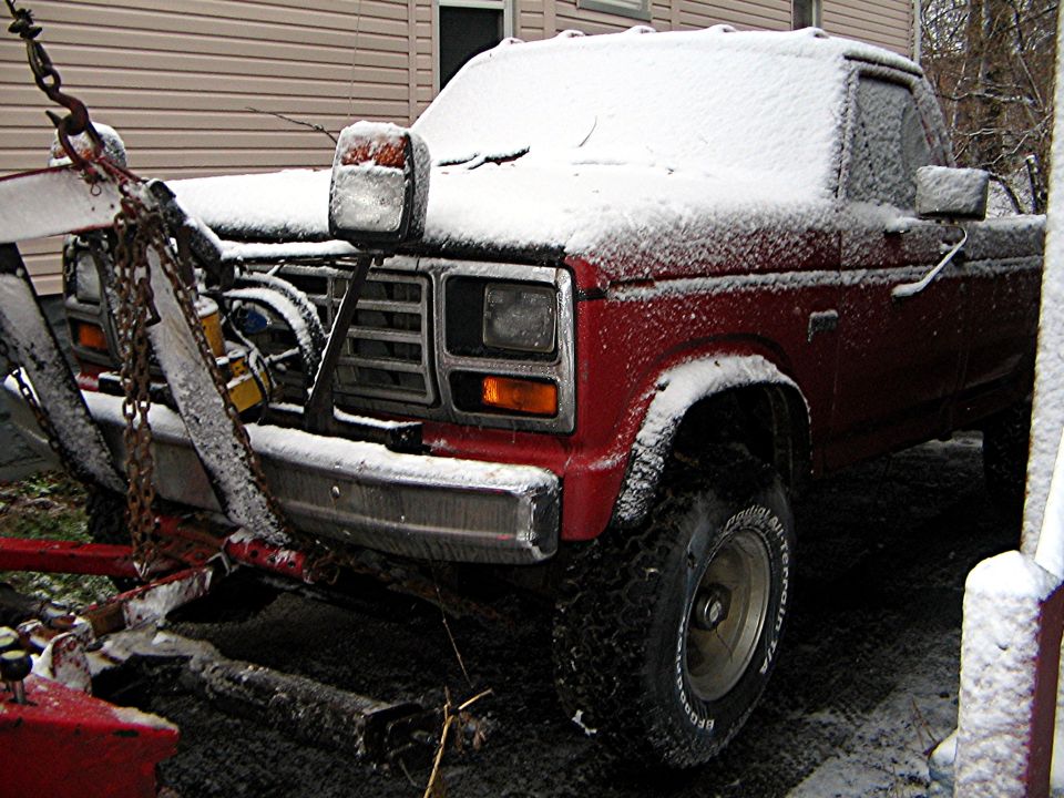Red 1983 Ford F-350 with snow plow in snow
