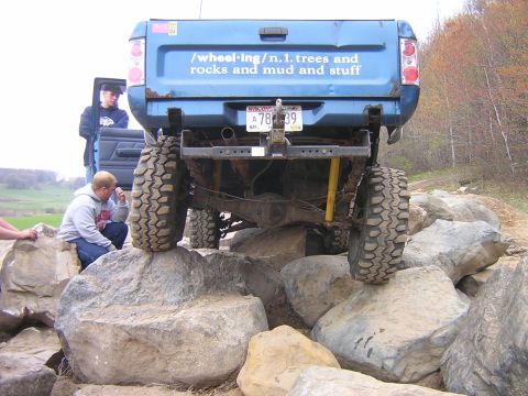 1977 Ford F-150 - A blue pickup truck navigates a rocky obstacle course with people observing the action.
