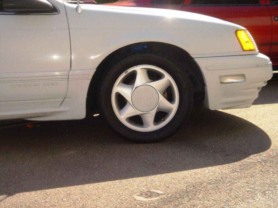 White sedan front fender and wheel with 'TAURUS SHO' text visible