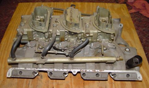 1969 Ford Fairlane - A triple carburetor intake manifold assembly is shown resting on a wooden surface.