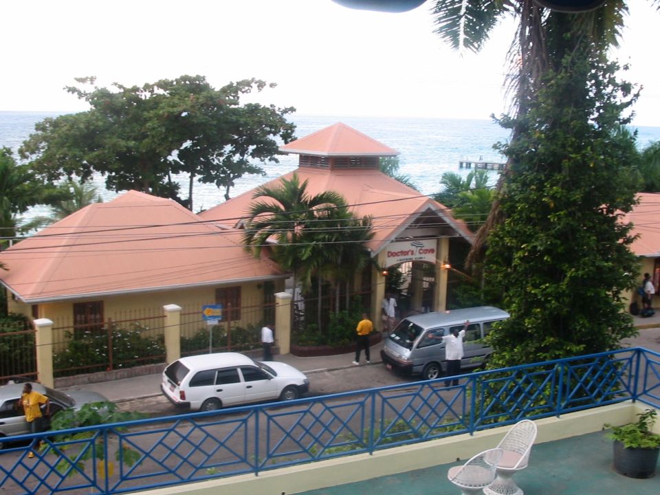 Doctor's Cave building with white station wagon and silver van parked outside