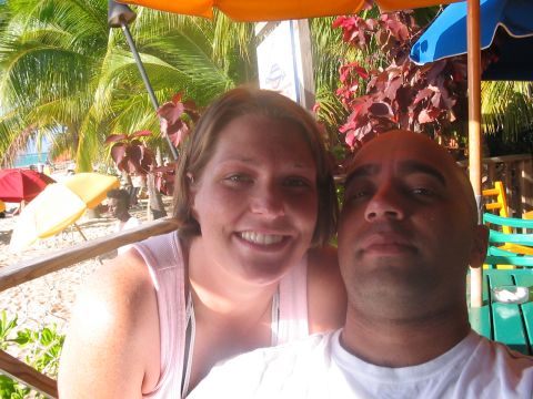 1991 Ford Bronco - A couple poses for a photo on a tropical beach, with palm trees and umbrellas in the background.