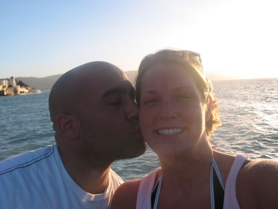 Couple kissing with ocean and buildings in background