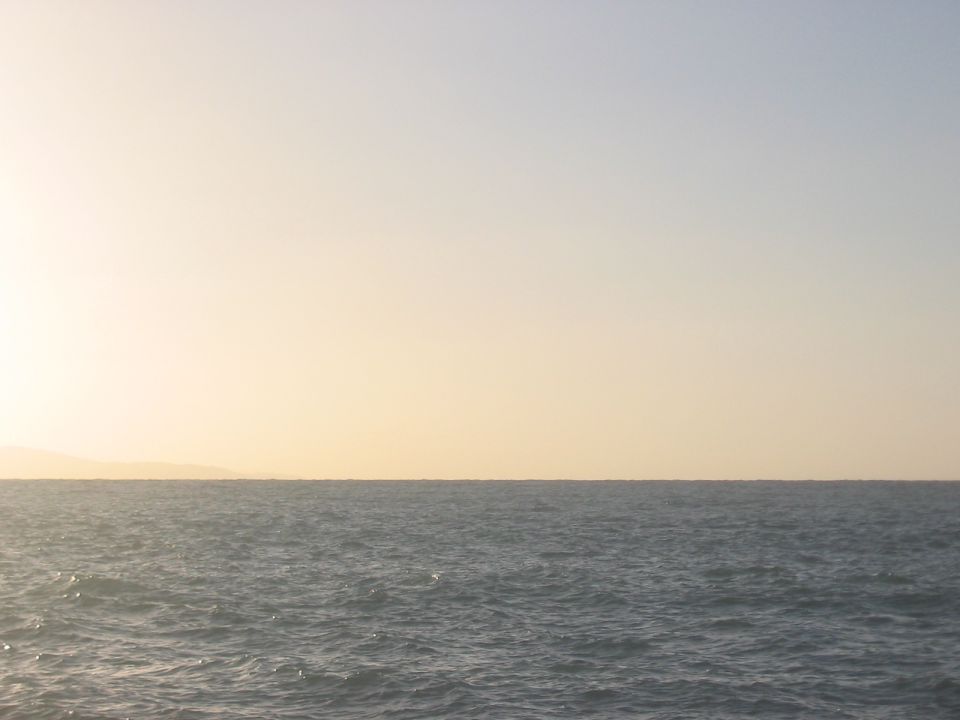 Ocean horizon under a pale yellow sky