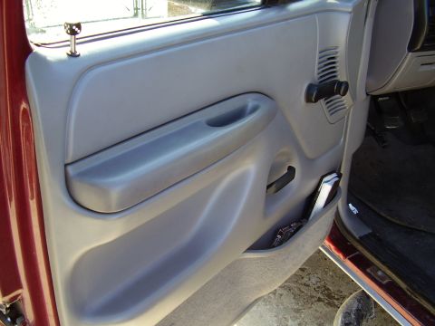 1996 Ford F-150 - The interior door panel of a 1996 Ford F-150 features a gray finish with a prominent armrest and a convenient storage pocket.