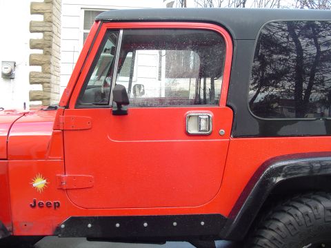 1989 Jeep YJ - The side profile of a red 1989 Jeep YJ shows its distinctive door and fender design.