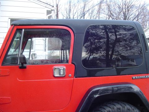 1989 Jeep YJ - Side view of a red 1989 Jeep YJ Wrangler with a black hardtop and fender flares.