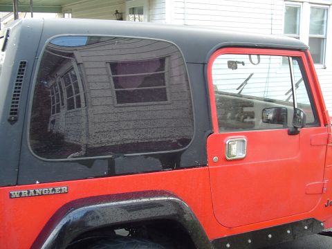 1989 Jeep YJ - This red Jeep Wrangler features a black hardtop and the distinctive Wrangler badging on its side.