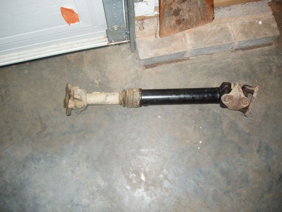 Automotive driveshaft with U-joints and slip yoke on a garage floor