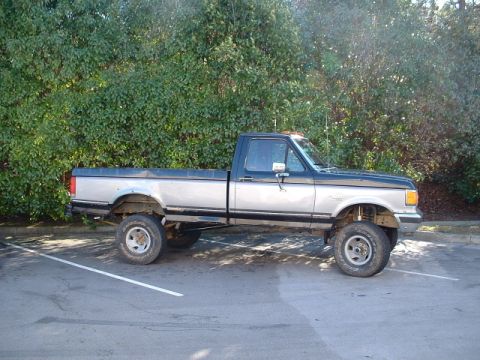 1987 Ford F-150 - Side view of a lifted 1987 Ford F-150 pickup truck with a two-tone paint scheme.