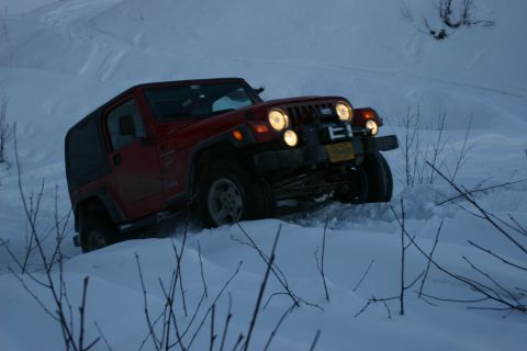 2003 Jeep TJ - 2003 Jeep TJ navigating a snowy trail with its headlights illuminated.