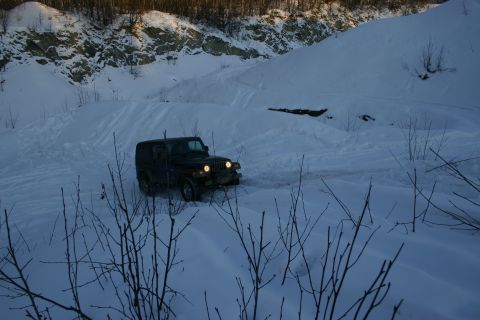 2003 Jeep TJ - A Jeep Wrangler navigates a snow-covered trail in a remote, hilly area during daylight.
