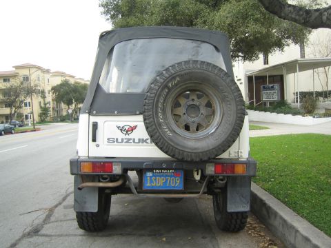 1987 Suzuki Samurai - Rear view of a 1987 Suzuki Samurai parked on a street, with a spare tire on the back.