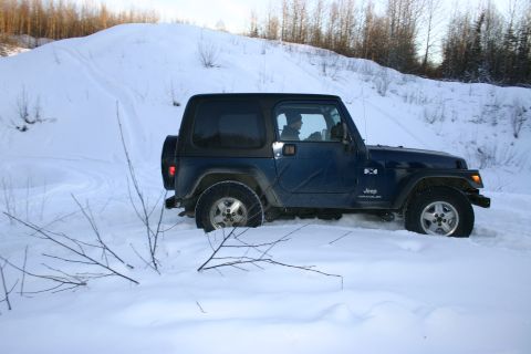 2003 Jeep TJ - A blue 2003 Jeep TJ navigates through a snowy landscape.