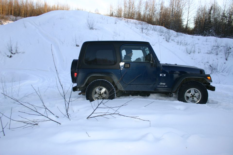 Blue 2003 Jeep TJ in snow, side view, with spare tire on rear