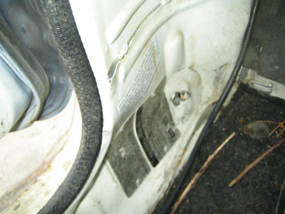 Close-up of a white vehicle's door jamb with a sticker and wiring harness