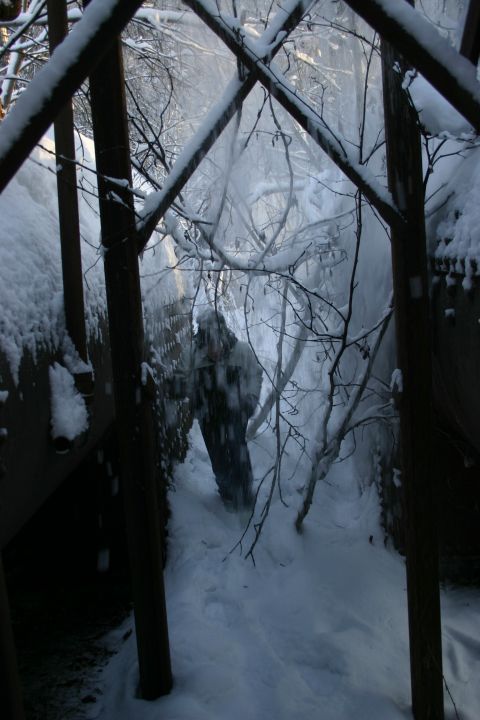 2003 Jeep TJ - A person navigates a snow-covered path surrounded by trees and industrial-looking structures.