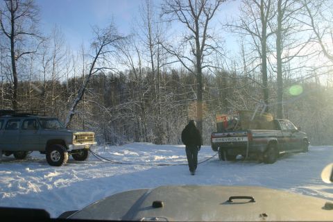 2003 Jeep TJ - A gray Chevrolet Suburban and a red Chevrolet pickup truck are seen in a snowy landscape, connected by a tow strap.