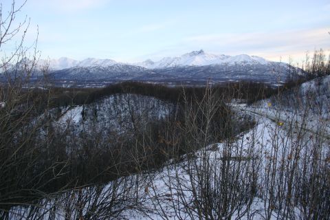 2003 Jeep TJ - A winter scene shows snow-covered mountains in the distance and a road cutting through a forest.