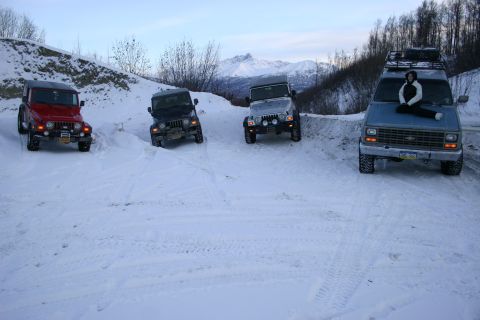 2003 Jeep TJ - A group of off-road vehicles navigate a snow-covered path, with a van parked to the side.