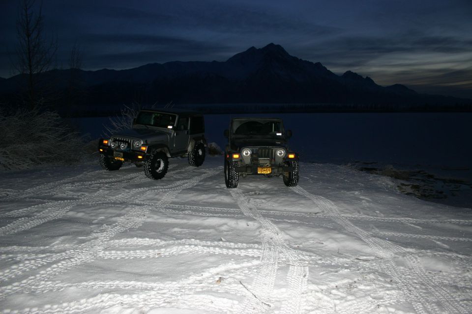 Two 2003 Jeep TJs parked in snow with mountains in background